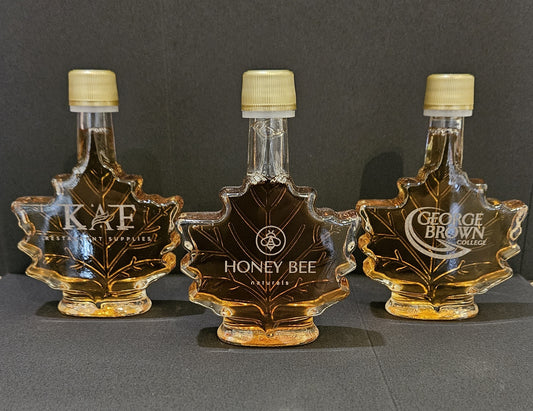 Three Maple leaf Etched maple syrup Bottles dark Backround